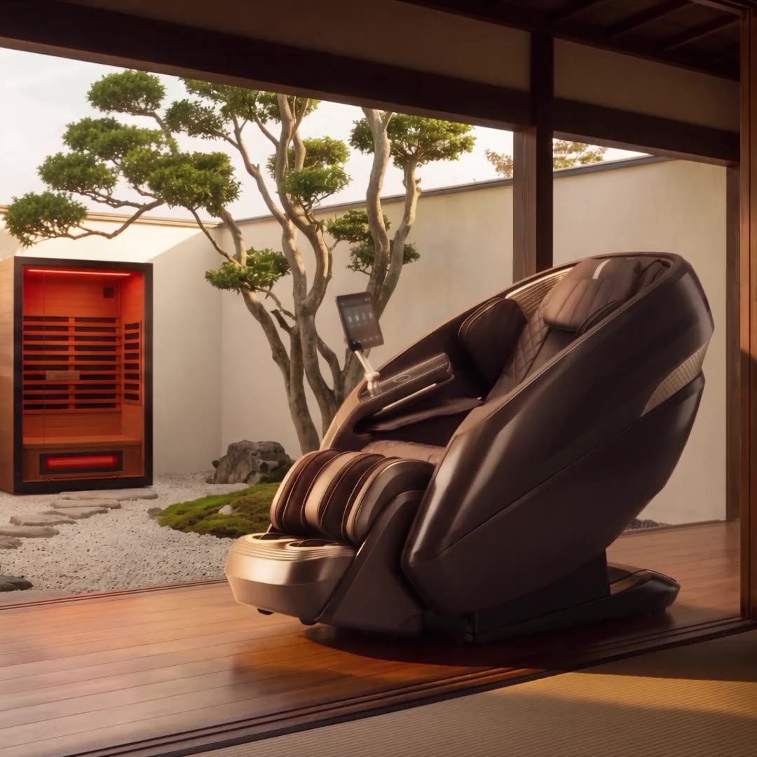 A Relaxe massage chair on a wood floor, looking out at a Japanese courtyard with the Caldera sauna glowing by the wall